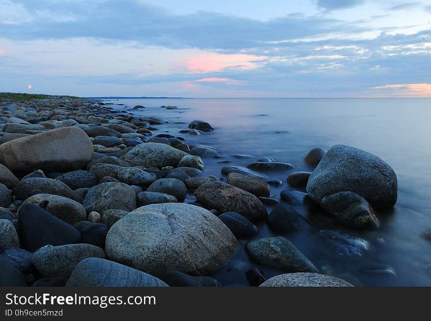 Pebbles on Beach Against Sky during Sunset