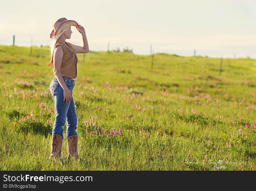 Woman Wearing Brown Cowboy Boots and Vest With Hat Under Blue Sky during Daytime