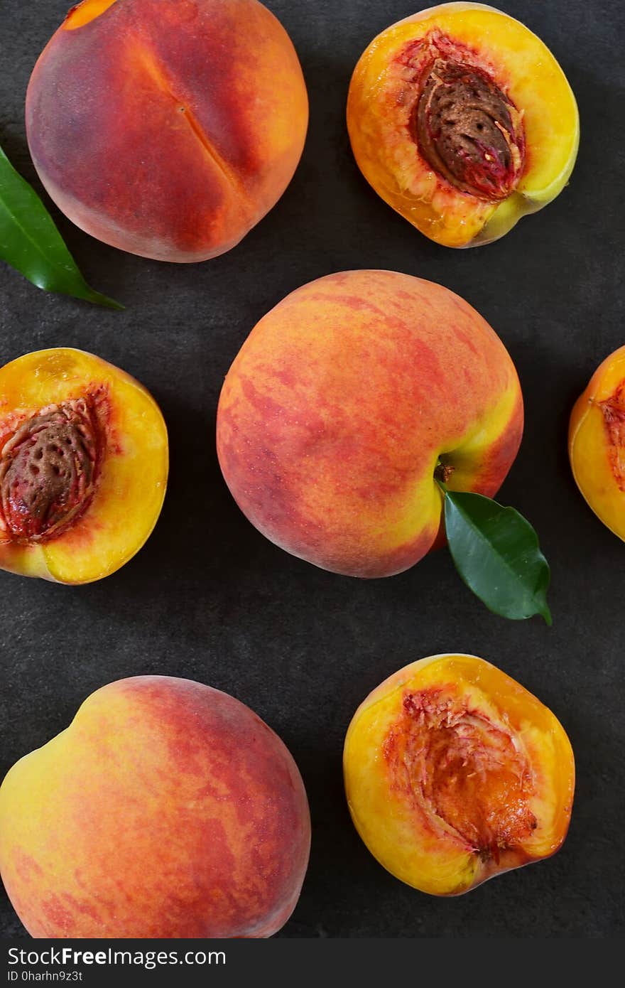 Fresh, juicy peaches on a black stone background.