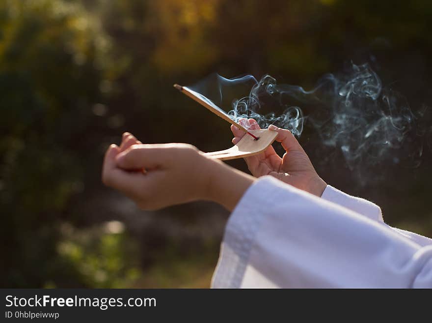 A boy in a kimono holds a burning incense stick, performing a mysterious rite. Sports, meditation, concentration, religion