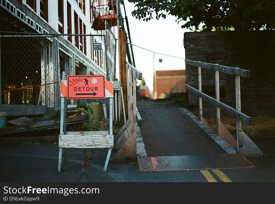 A construction site with a sign pointing to a a detour around it.