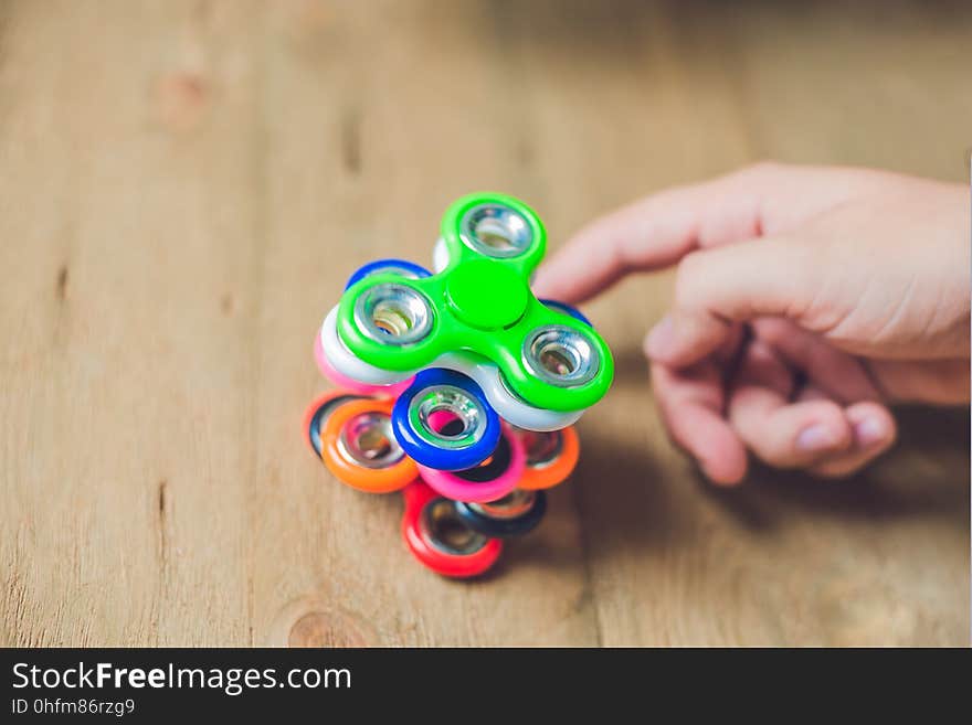 A man hand holding hand spinner or fidget spinner over wooden ba