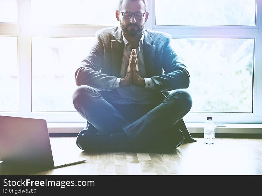 Businessman doing yoga in lotus pose at office workplace with laptop