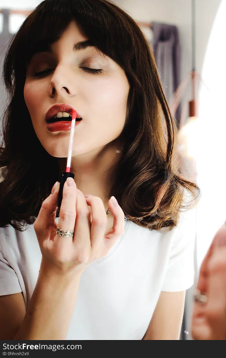 Portrait of a beautiful woman, dyes her lips lipstick pink