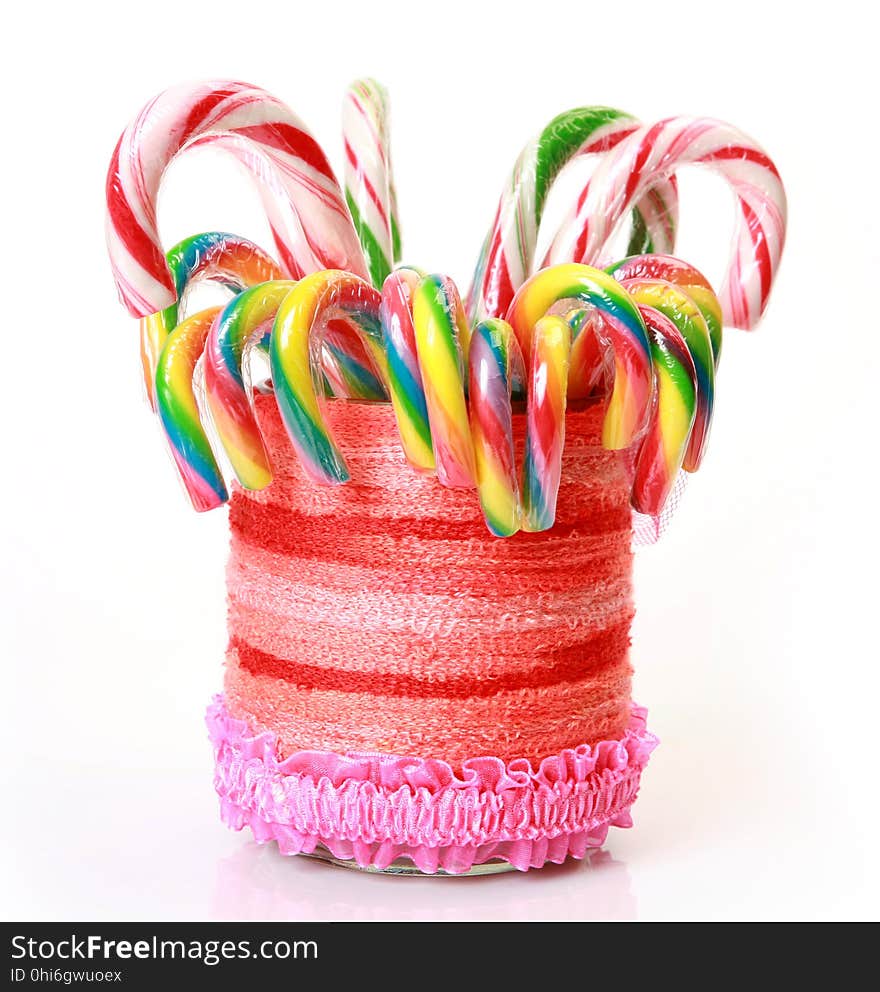 Colored candy in a glass decorated with threads on a white background. Colored candy in a glass decorated with threads on a white background