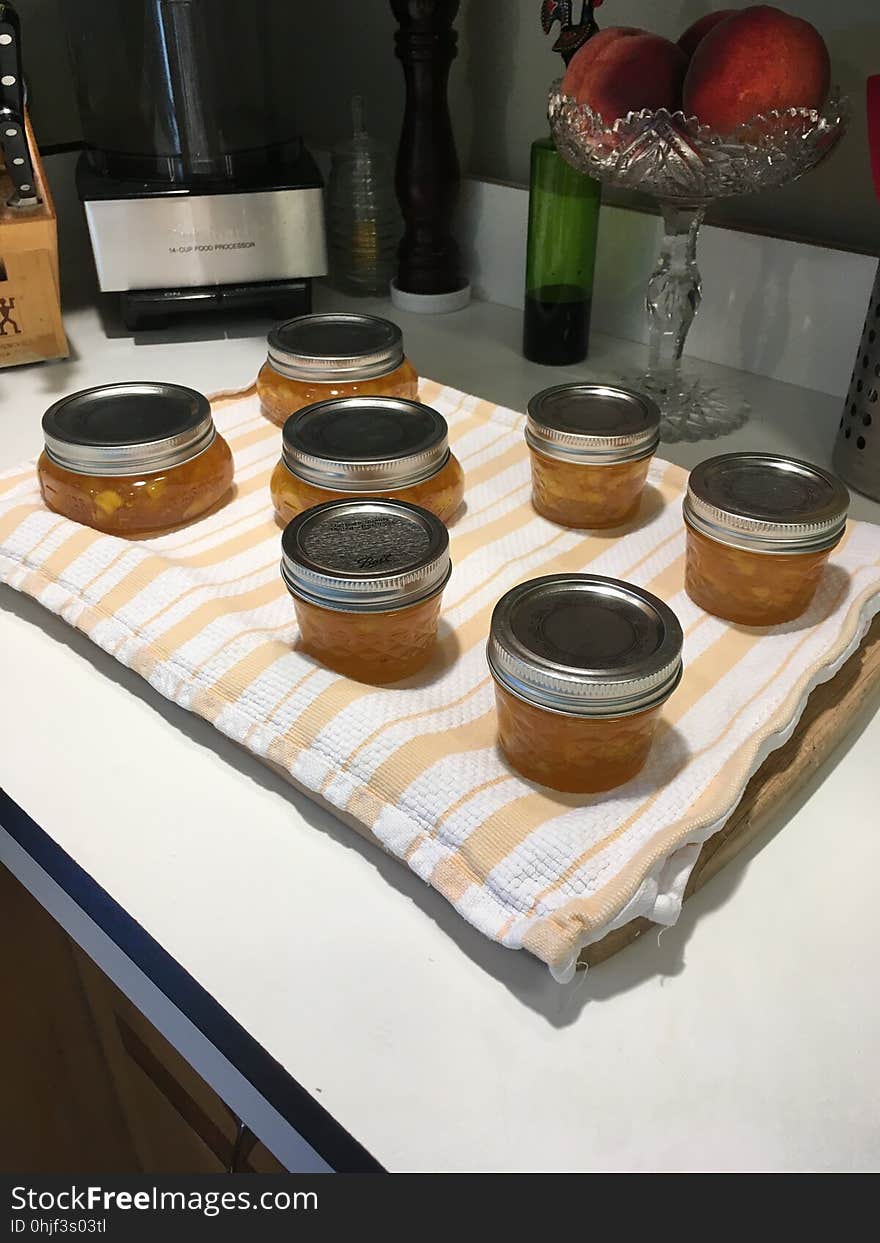 Peach jam cooling on wooden cutting board covered with kitchen towel