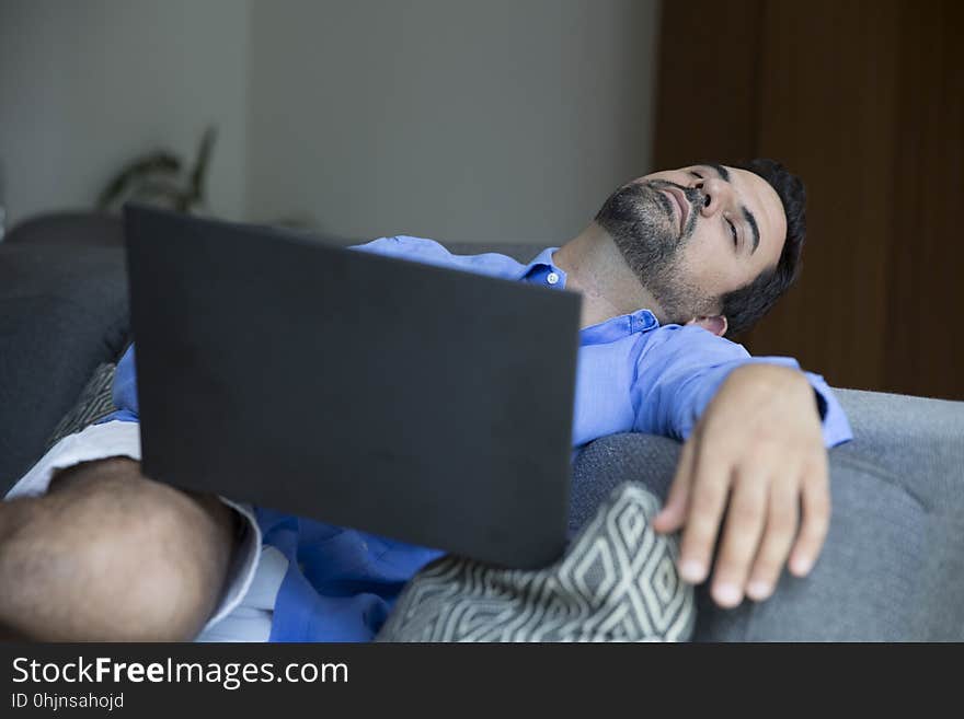 Arab man working in his laptop on a sofa in his city apartment