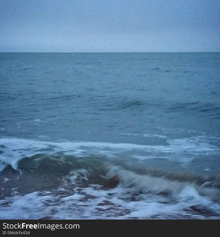 A view of the sea with waves hitting ashore at dusk.