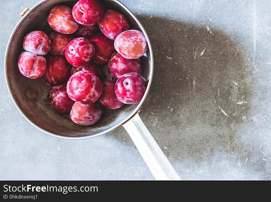 Plums of different varieties in an old metal colander on gray concrete background. Top view. Agriculture, Gardening, Harvest Concept. Plums of different varieties in an old metal colander on gray concrete background. Top view. Agriculture, Gardening, Harvest Concept.