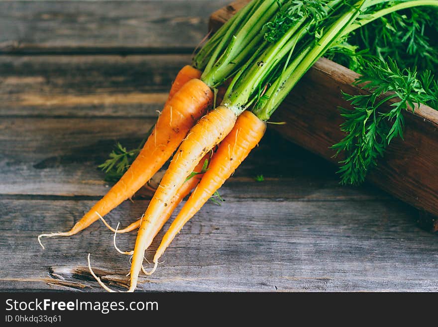 Fresh carrots with green tops in a wooden box, on a wooden background, harvest, autumn. Fresh carrots with green tops in a wooden box, on a wooden background, harvest, autumn