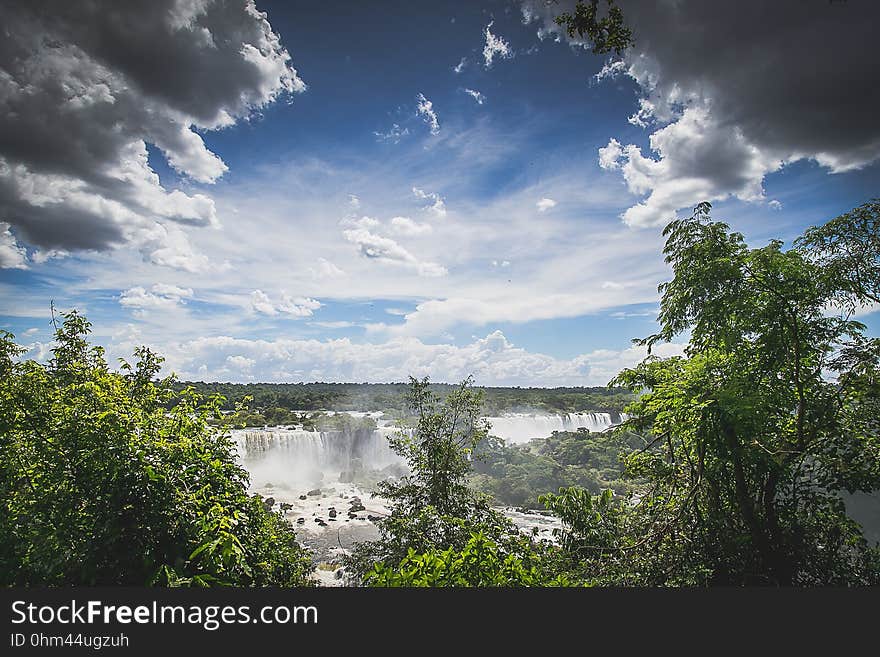 Waterfall landscape through green trees against blue skies on sunny day. Waterfall landscape through green trees against blue skies on sunny day.