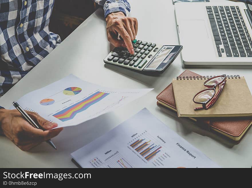 Business documents on office table with smartphone and tablet and graph financial and businessman working in the background