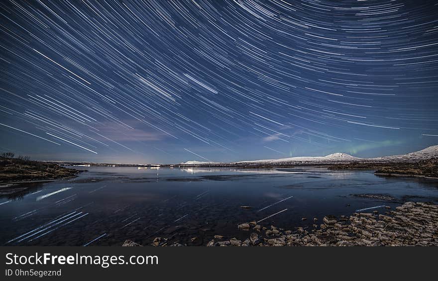 Star trails in night sky over waterfront. Star trails in night sky over waterfront.