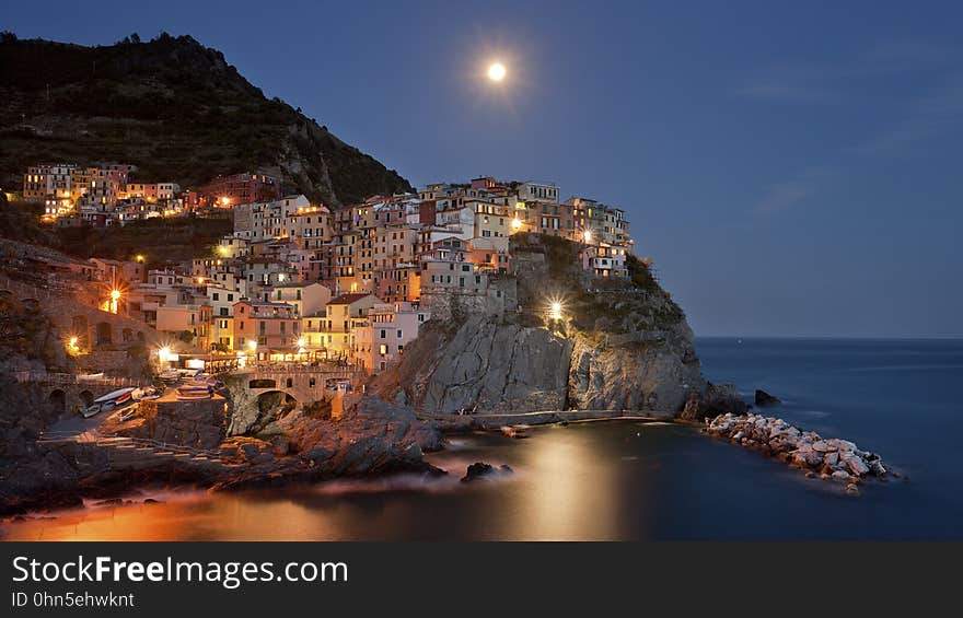 Coastal town on hillside illuminated at night with moonlight. Coastal town on hillside illuminated at night with moonlight.