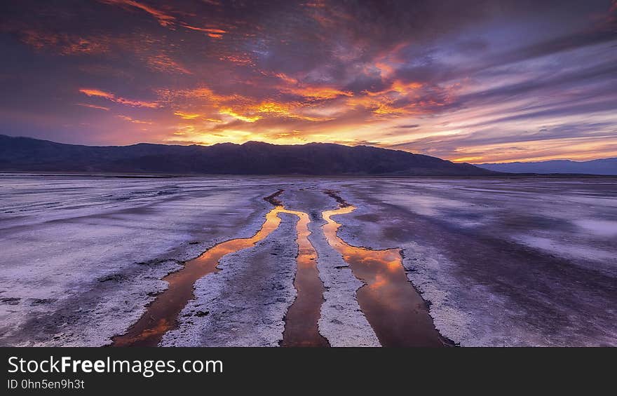 Waves crash during low tide on a beach at sunset. Waves crash during low tide on a beach at sunset.