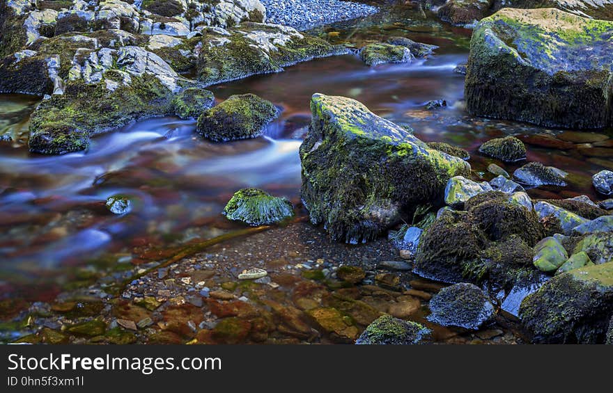 Blur of water over moss covered rocks in small stream. Blur of water over moss covered rocks in small stream.