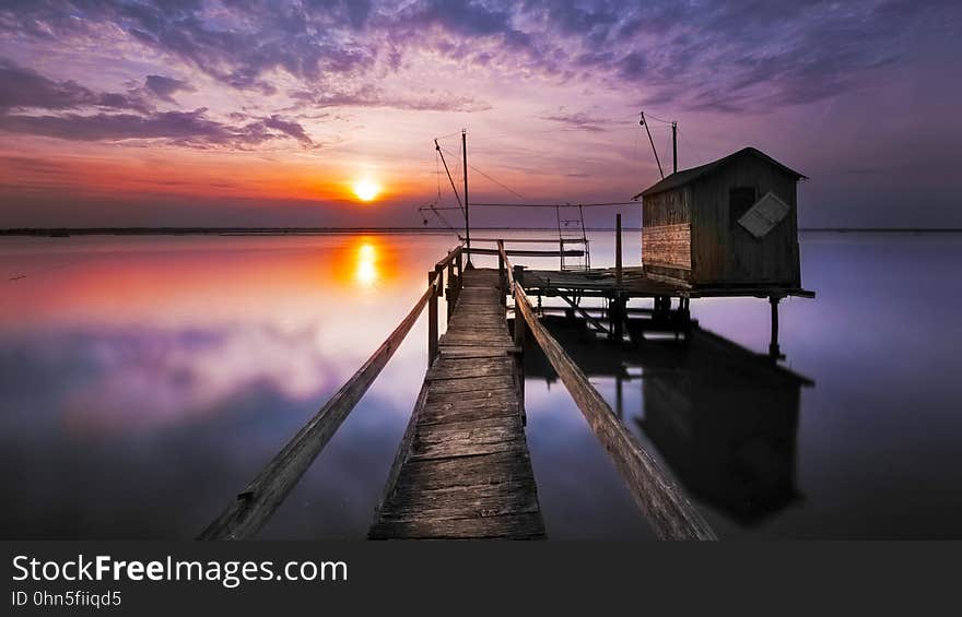 Sunset on the sea with a wooden pier and a boathouse. Sunset on the sea with a wooden pier and a boathouse.