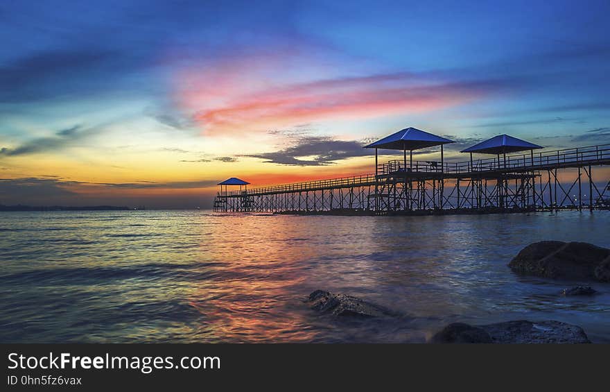 A pier in the sea at sunset. A pier in the sea at sunset.