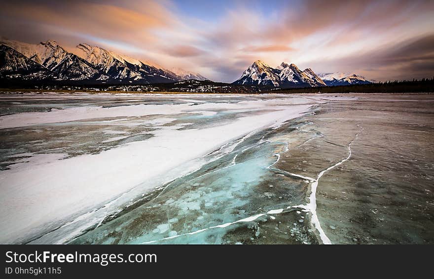 Sunrise over Canadian Rockies with snow and ice in foreground.