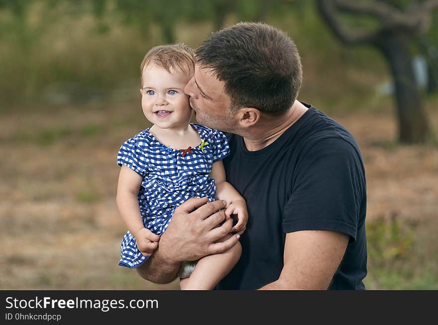 Father is holding his beautiful baby with eyes blue. Father and daughter playing outdoors. Smiling. Father is holding his beautiful baby with eyes blue. Father and daughter playing outdoors. Smiling