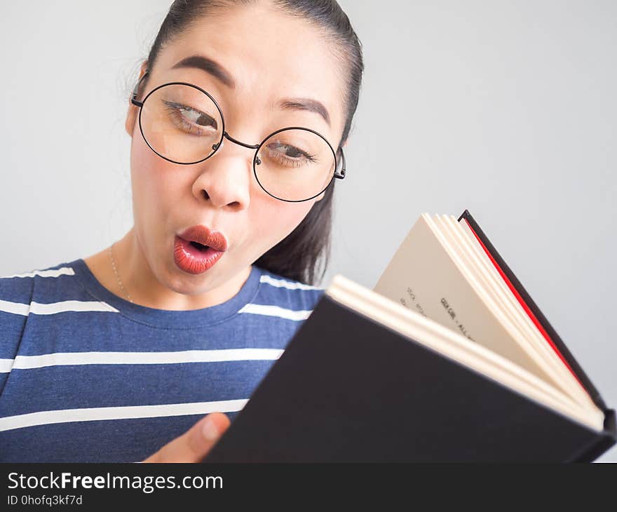 Nerdy Asian woman got a surprised idea from the book.