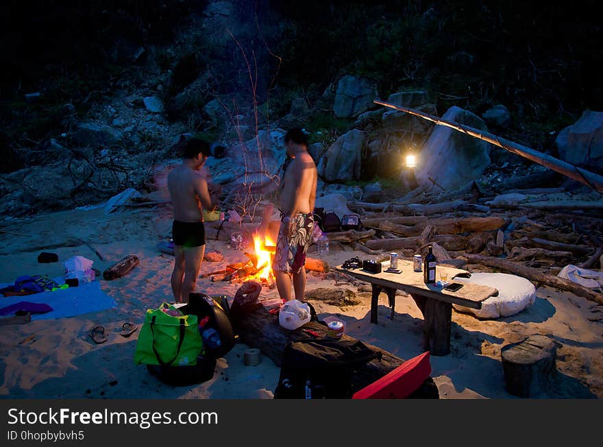 Campers cooking over bonfire on sandy beach. Campers cooking over bonfire on sandy beach.