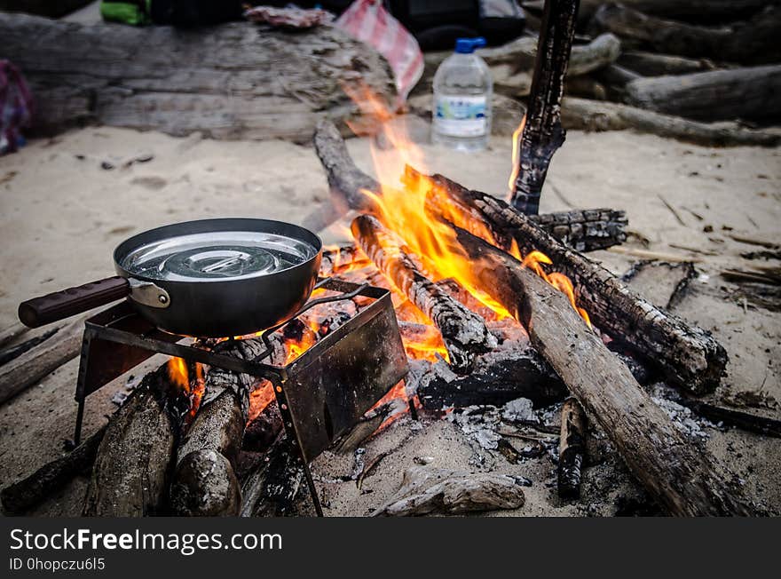 Skillet on grate over campfire on sandy beach. Skillet on grate over campfire on sandy beach.