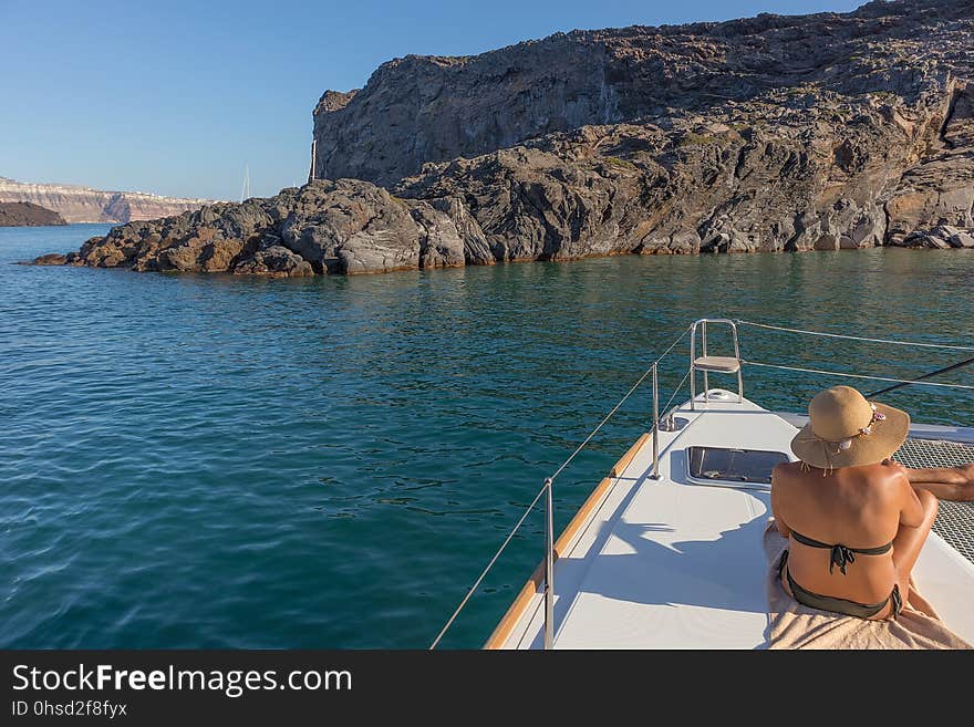 Woman sitting on the bow of boat, santorini greece