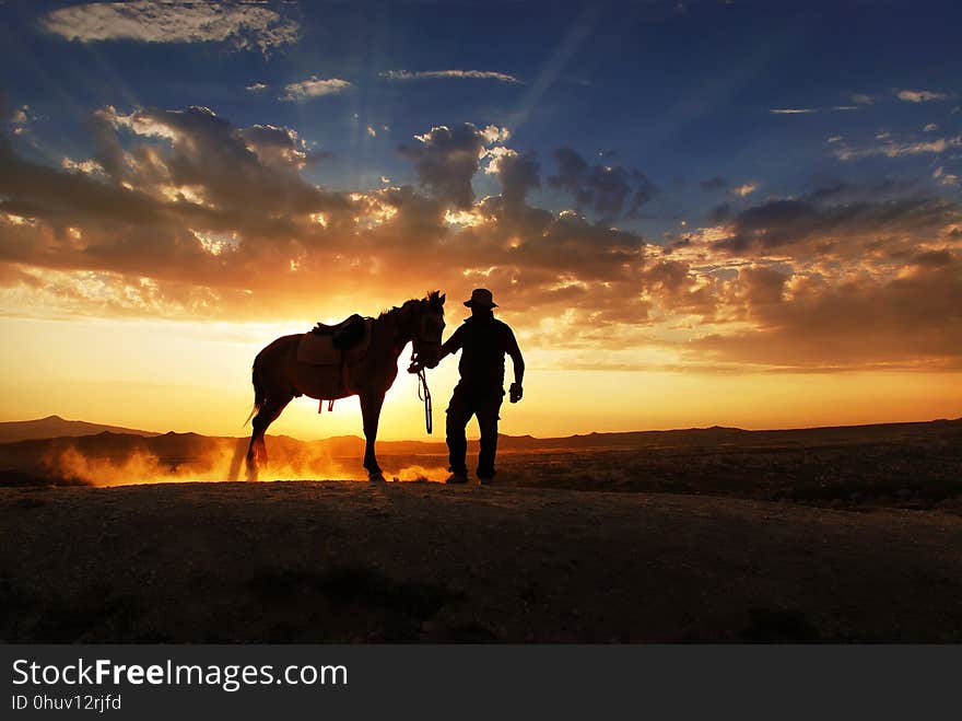 A Cowboy Is Standing With His Horse