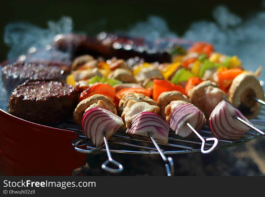 Low angle full BBQ with burgers sausages chicken kebabs on skewers and a bit of smoke. Low angle full BBQ with burgers sausages chicken kebabs on skewers and a bit of smoke