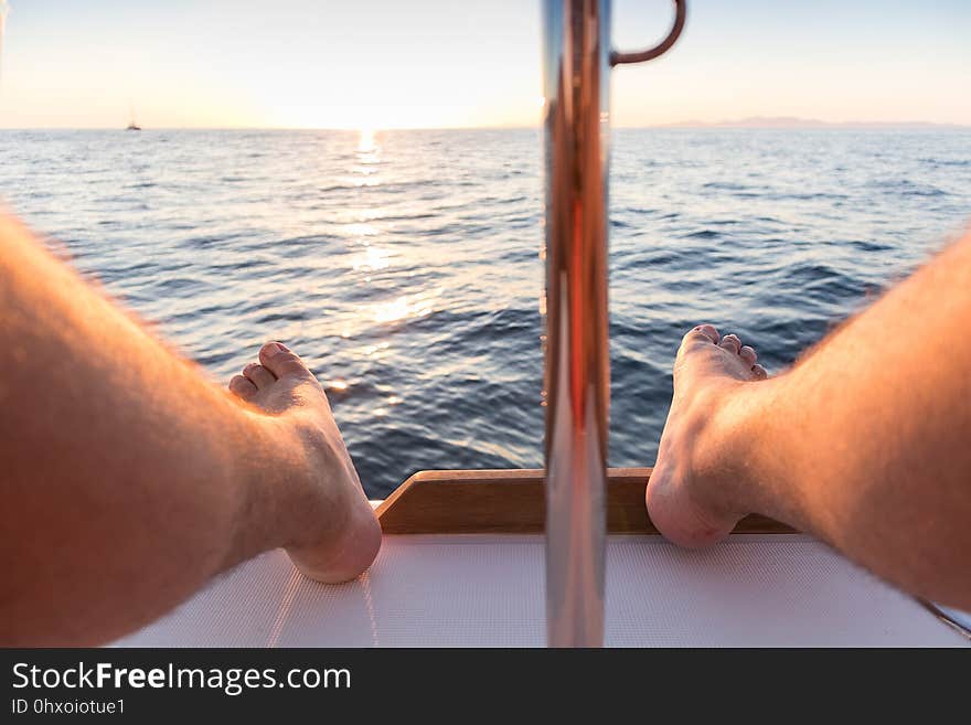 Feet of man with view of the sea and sunset.