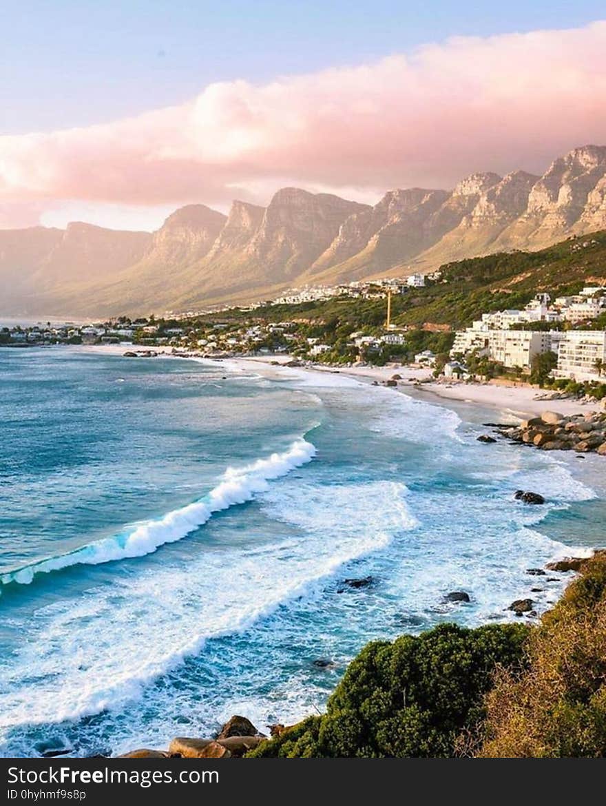 Waves crashing on the shores of a beautiful beach surrounded by mountains.