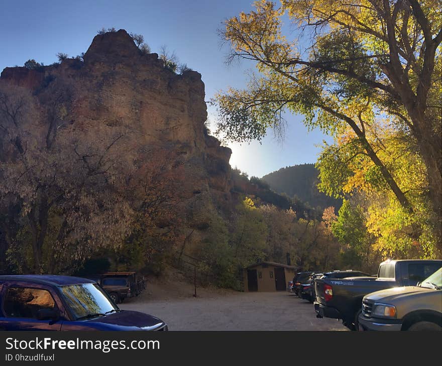 A parking lot with cars next to a stone cliff.