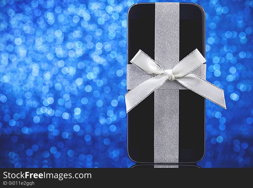 Smartphone gift for Christmas on blue defocused background