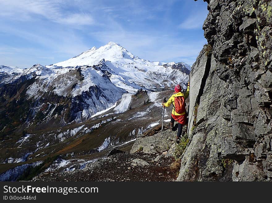 A hiker looking at a snowcapped mountain peak. A hiker looking at a snowcapped mountain peak.