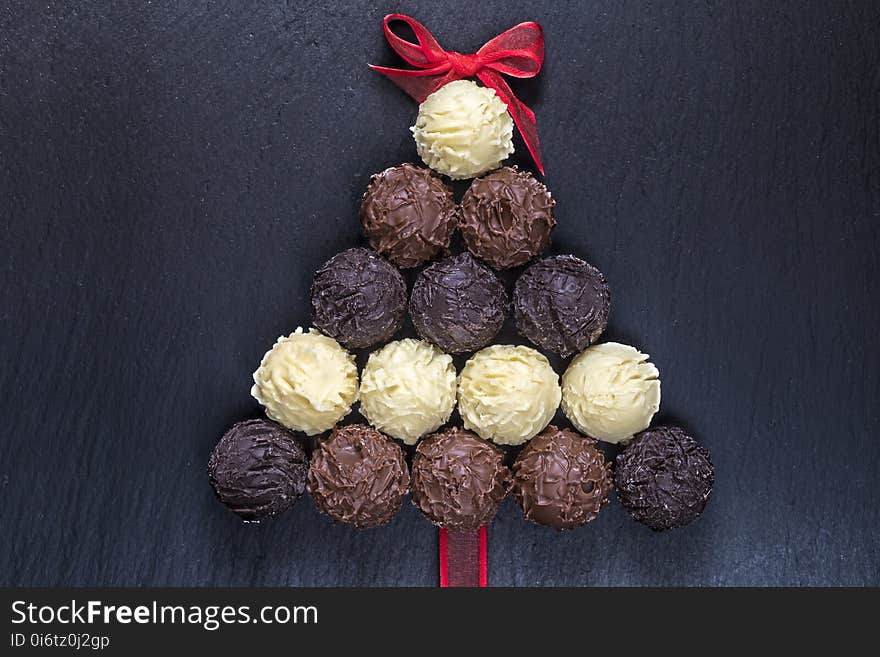 Chocolate truffles shaped Christmas tree on black stone table top view. Chocolate truffles shaped Christmas tree on black stone table top view.