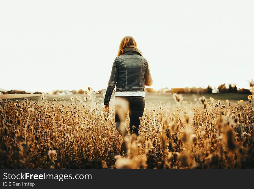 Woman in Blue Denim Jacket Walking on Field