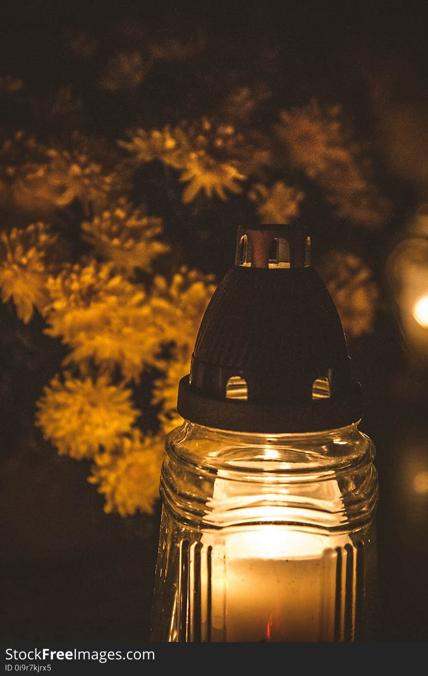 A burning candle and chrysanthemums at a cemetery