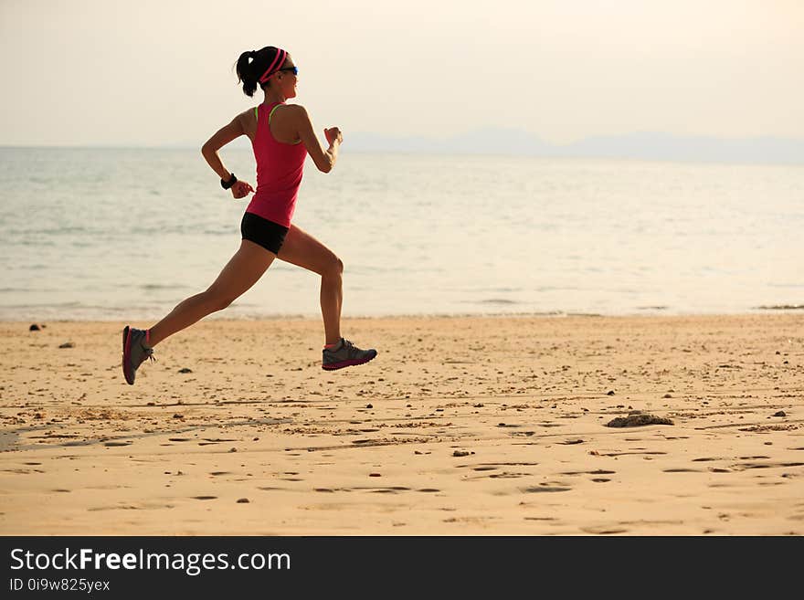 Sporty woman runner running on seaside sandy beach