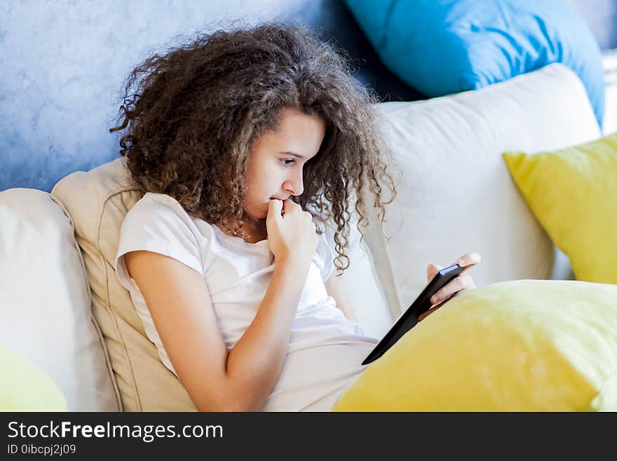 Teen Girl Resting And Usiing Digital Tablet On Sofa At Home