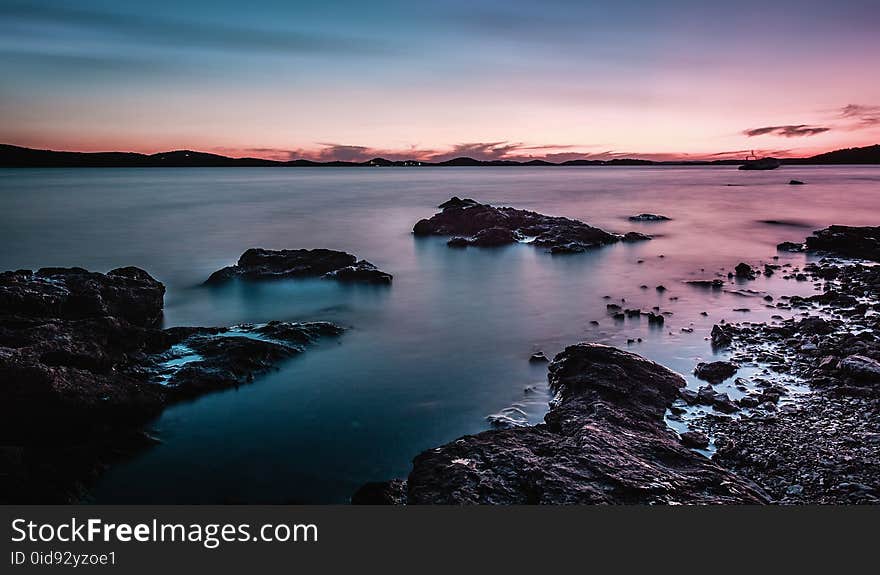 Rock Formation On Body Of Water During Golden Hour