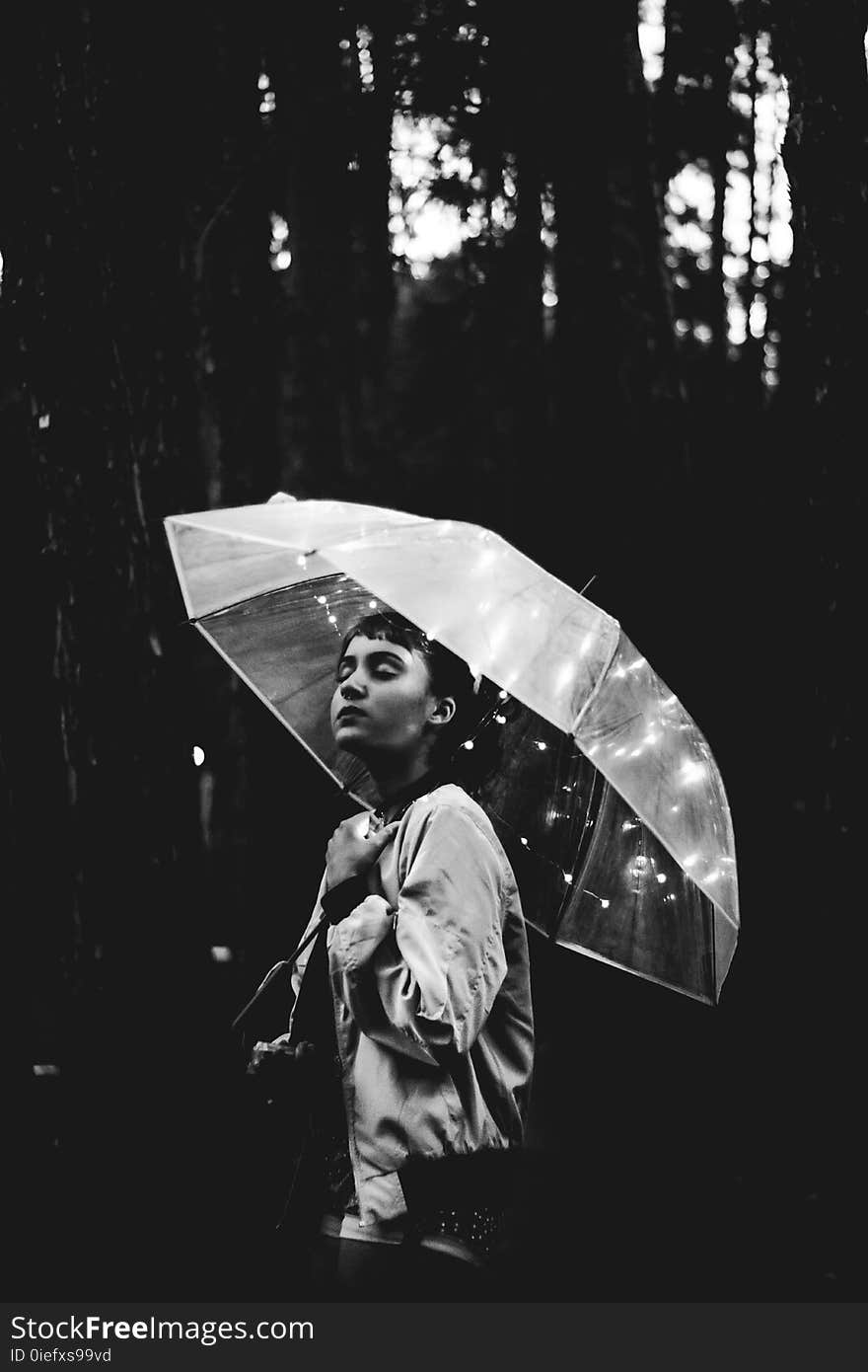 Grayscale Image of Woman Walking Through the Rain While Holding Umbrella