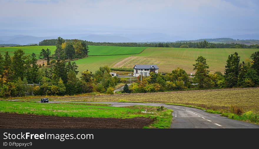 Rural houses with fields in Biei, Hokkaido, Japan. Biei is a small town surrounded by a picturesque landscape of gently rolling hills and vast fields. Rural houses with fields in Biei, Hokkaido, Japan. Biei is a small town surrounded by a picturesque landscape of gently rolling hills and vast fields.