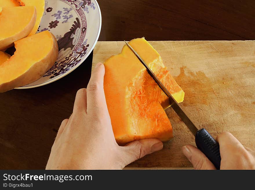 Top view of woman hands that cutting the pumpkin on wooden board