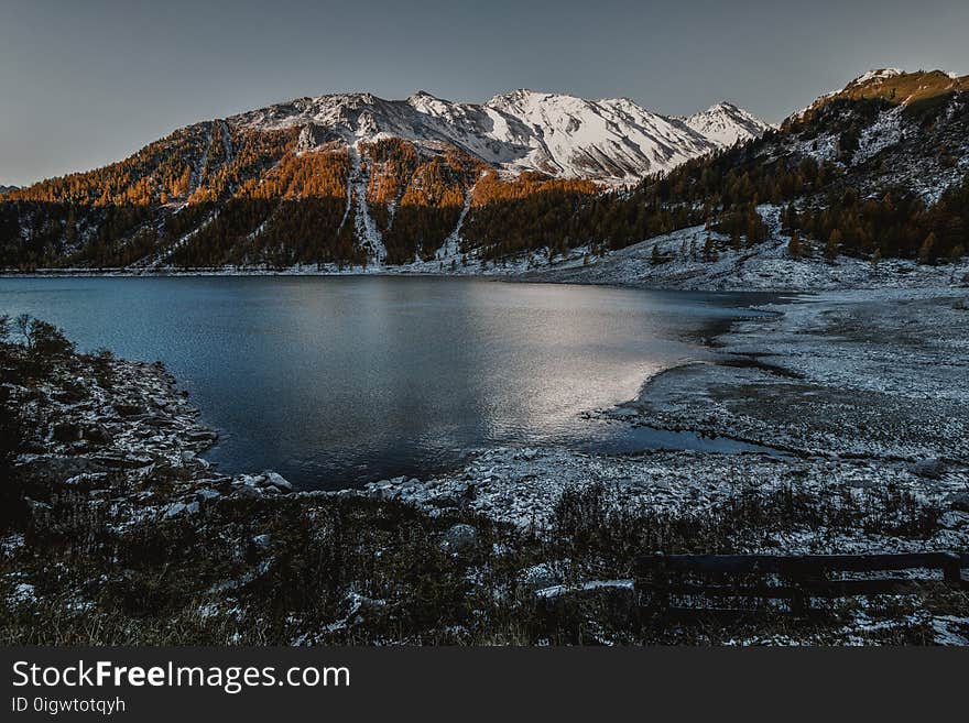 Brown and White High Rise Mountain Beside of Body of Water