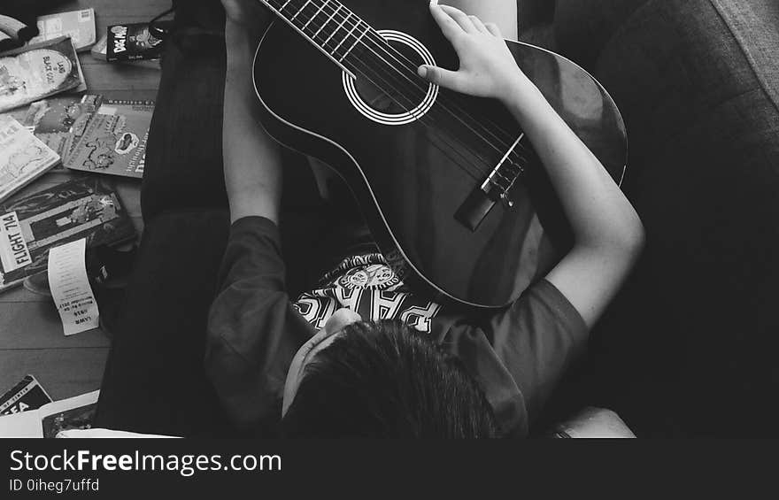 Man Playing Guitar Lying on Couch in Grayscale Photography