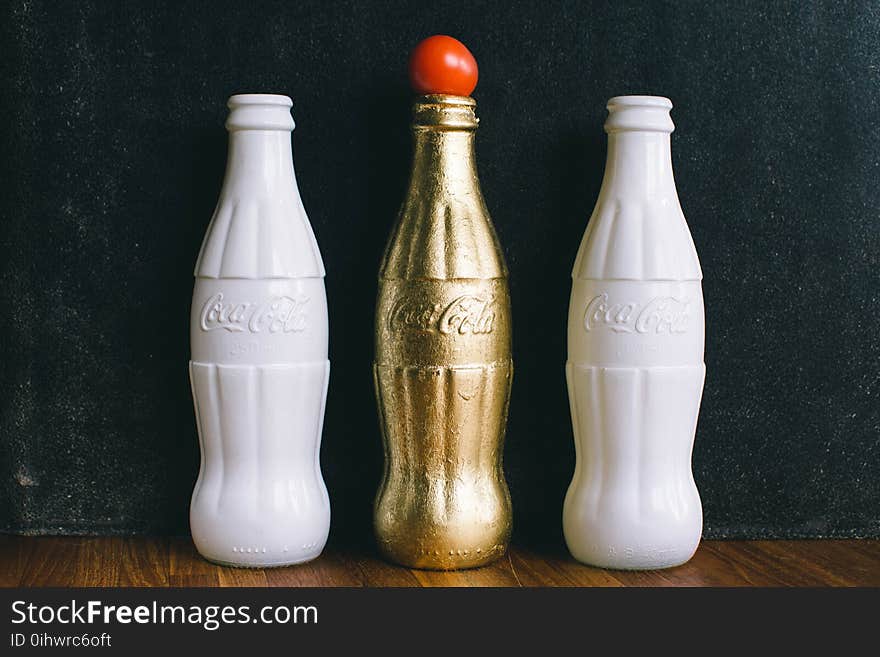 Three White and Brass Coca-cola Bottles