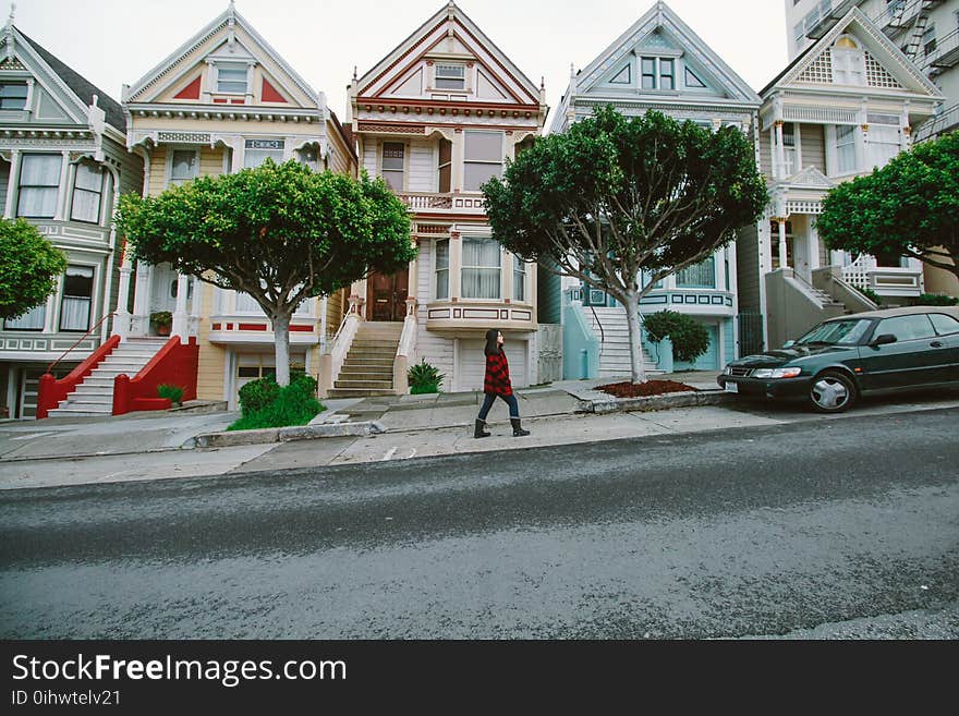 Woman Walking Toward Black Sedan Parked In Front of Colorful Houses