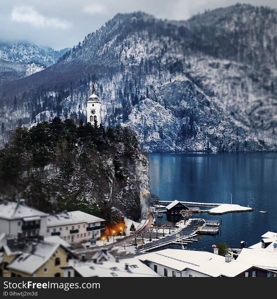 Snow Covered Mountain Houses Near Body of Water at Daytime