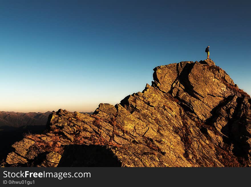 Man Standing on Top of Rock at Daytime